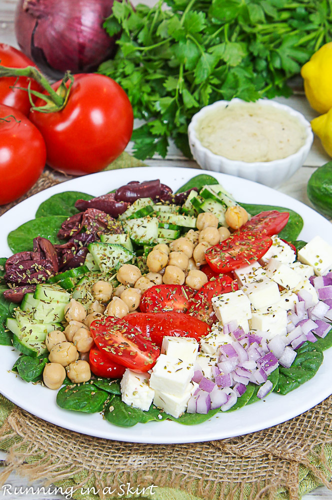 Mediterranean Chopped Salad on a white plate with the dressing in the background.